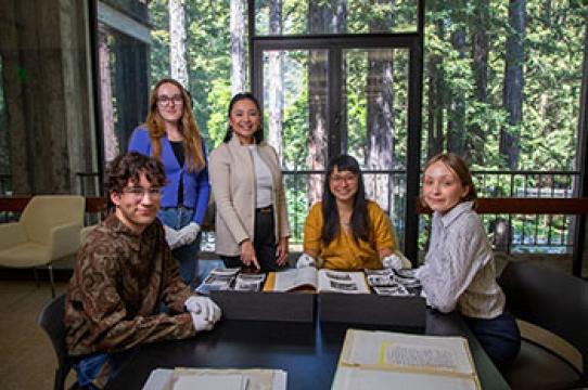Members of the WIITH team looking at photographs and documents housed in UCSC Special Collections. Center, Christina Ayson Plank (WIITH head curator and digital archive co-director). Photo by Carolyn Lagattuta